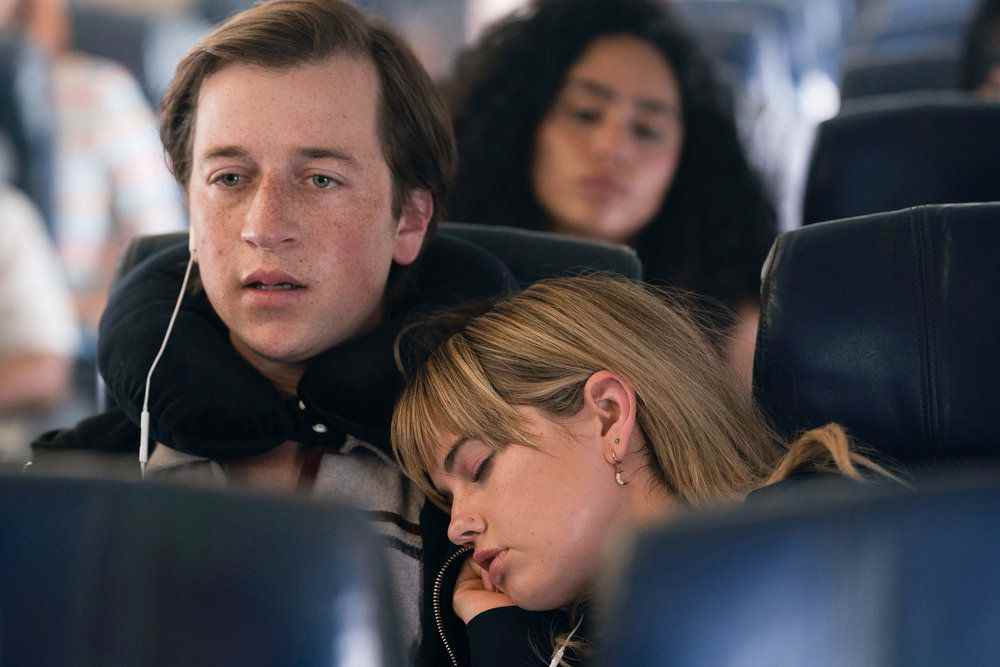 Sam a l'air choqué dans un avion pendant que sa petite amie dort sur son épaule dans The Resort