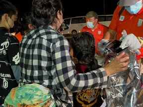 Des agents de l'Institut national mexicain des migrations (INM) aident un groupe de migrants après avoir été secourus avec d'autres migrants qui ont été abandonnés à l'intérieur d'une caravane, dans la ville d'Acayucan, dans l'État de Veracruz, au Mexique, le 27 juillet 2022.