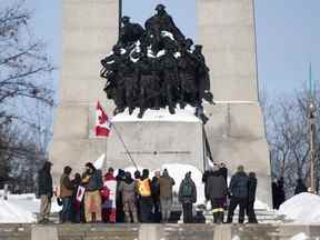 Des gens entourent la tombe du soldat inconnu au Monument commémoratif de guerre du Canada lors d'un rassemblement contre les restrictions liées à la COVID-19 à Ottawa le 30 janvier 2022.