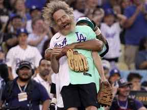 L'acteur Bryan Cranston est soulevé par l'ancien joueur des Dodgers de Los Angeles Andre Ethier lors du match de softball All Star Celebrity de la MLB, le samedi 16 juillet 2022, à Los Angeles.