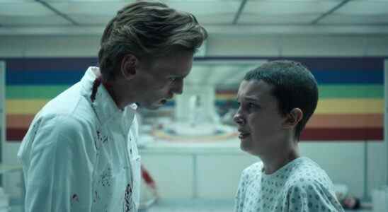 A blonde man in a white coat intimidates a teen girl with buzzed brown hair inside a playroom; still from "Stranger Things 4."