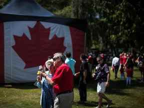 Un couple âgé mange des cornets de crème glacée près d'un grand drapeau canadien lors des festivités de la fête du Canada à West Vancouver le 1er juillet 2019.