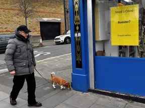 Un homme promène son chien devant une pharmacie annonçant la disponibilité des injections de rappel contre la maladie à coronavirus (COVID-19), à Dublin, en Irlande, le 25 janvier 2022.