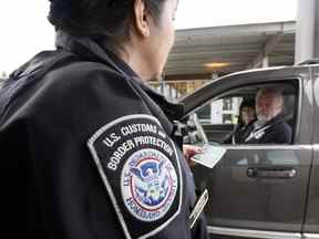 Un agent des douanes et de la protection des frontières des États-Unis parle avec un couple utilisant des cartes d'identité NEXUS à un poste frontalier entre le Canada et les États-Unis à Blaine, Wash.
