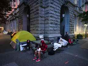 Des gens campent pendant la nuit dans une file d'attente devant un bureau des passeports de Service Canada à Vancouver le 22 juin 2022.