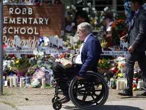 Le gouverneur du Texas, Greg Abbott, passe devant un mémorial à l'extérieur de la Robb Elementary School pour honorer les victimes tuées lors d'une fusillade dans une école à Uvalde, Texas, le 29 mai 2022.