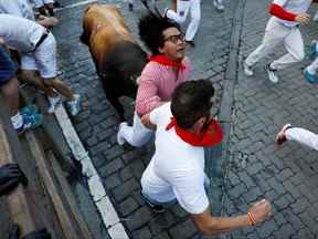 Un coureur est frappé par un taureau lors de la course des taureaux au festival de San Fermin à Pampelune, Espagne, le 11 juillet 2022.