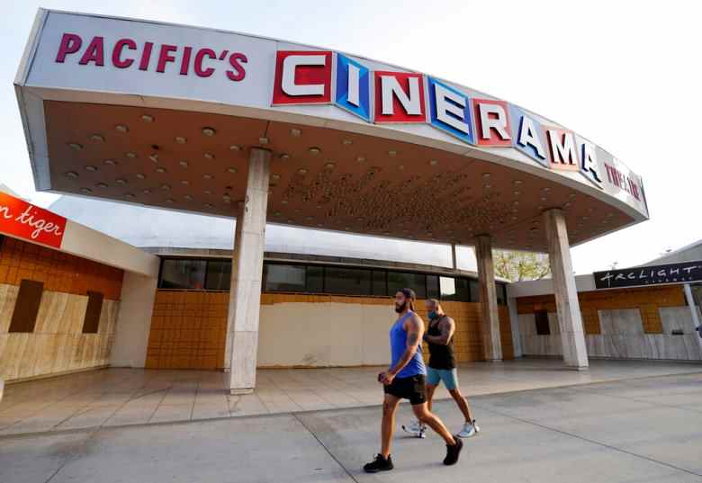 Des piétons passent devant le cinéma Cinerama Dome fermé et fermé, le lundi 12 avril 2021, à Los Angeles.  Pacific Theatres, qui exploite quelque 300 écrans en Californie, y compris les théâtres bien-aimés ArcLight et l'historique Cinerama Dome à Hollywood, a déclaré lundi qu'il ne rouvrirait pas.  Les fans, dont de nombreux acteurs, se sont rendus sur les réseaux sociaux pour partager des souvenirs de la chaîne de théâtre et faire pression pour qu'elle soit sauvée.  (AP Photo/Chris Pizzello)