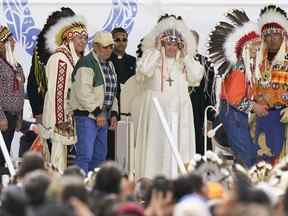 Le pape François enfile une coiffe lors d'une visite avec des peuples autochtones à Maskwaci, l'ancien pensionnat Ermineskin, le lundi 25 juillet 2022, à Maskwacis, en Alberta.