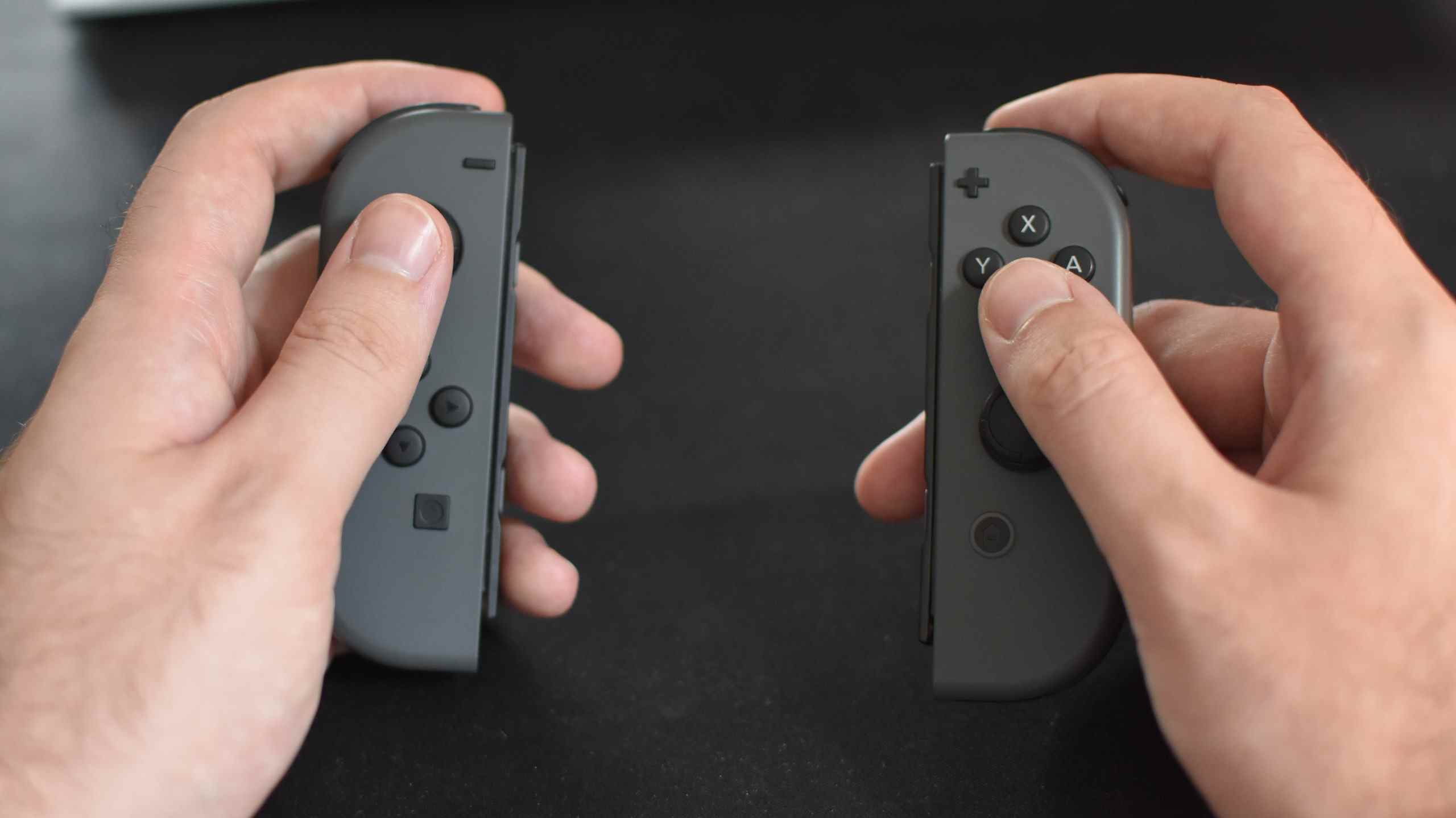 Une paire de mains tenant un ensemble de Nintendo Joy-Cons.