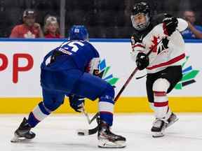 Connor Bedard (16) d'Équipe Canada tire à travers les jambes de Simon Groch (25) d'Équipe Slovaquie au cours de la deuxième période lors de l'action du Championnat mondial de hockey junior à Rogers Place à Edmonton le jeudi 11 août 2022.