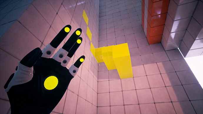 Un gant tend la main vers un mur blanc et un tas de cubes jaunes dans QUBE (2022).