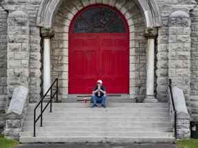 Un sympathisant du Peuple uni du Canada (TUPOC) prie sur les marches d'une ancienne église St. Brigid's dans la Basse-Ville.  Dimanche 21 août 2022.
