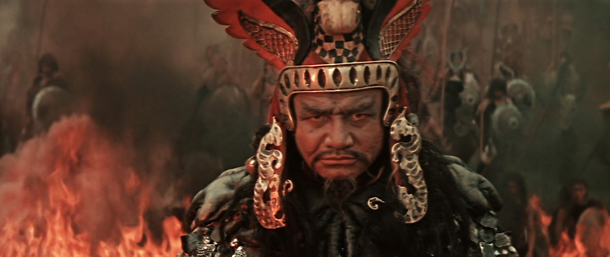 Un guerrier en gros plan dans une coiffe rouge et or vibrante au milieu d'une bataille acharnée à Ilya Muromets