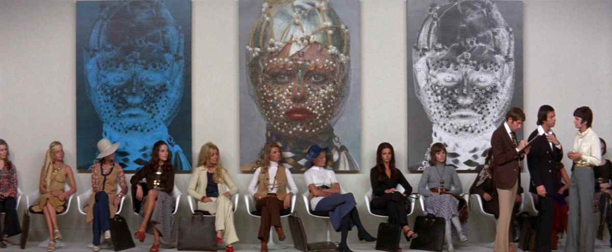 Un groupe de femmes, dont Jane Fonda, s'assoient en ligne devant trois tableaux.