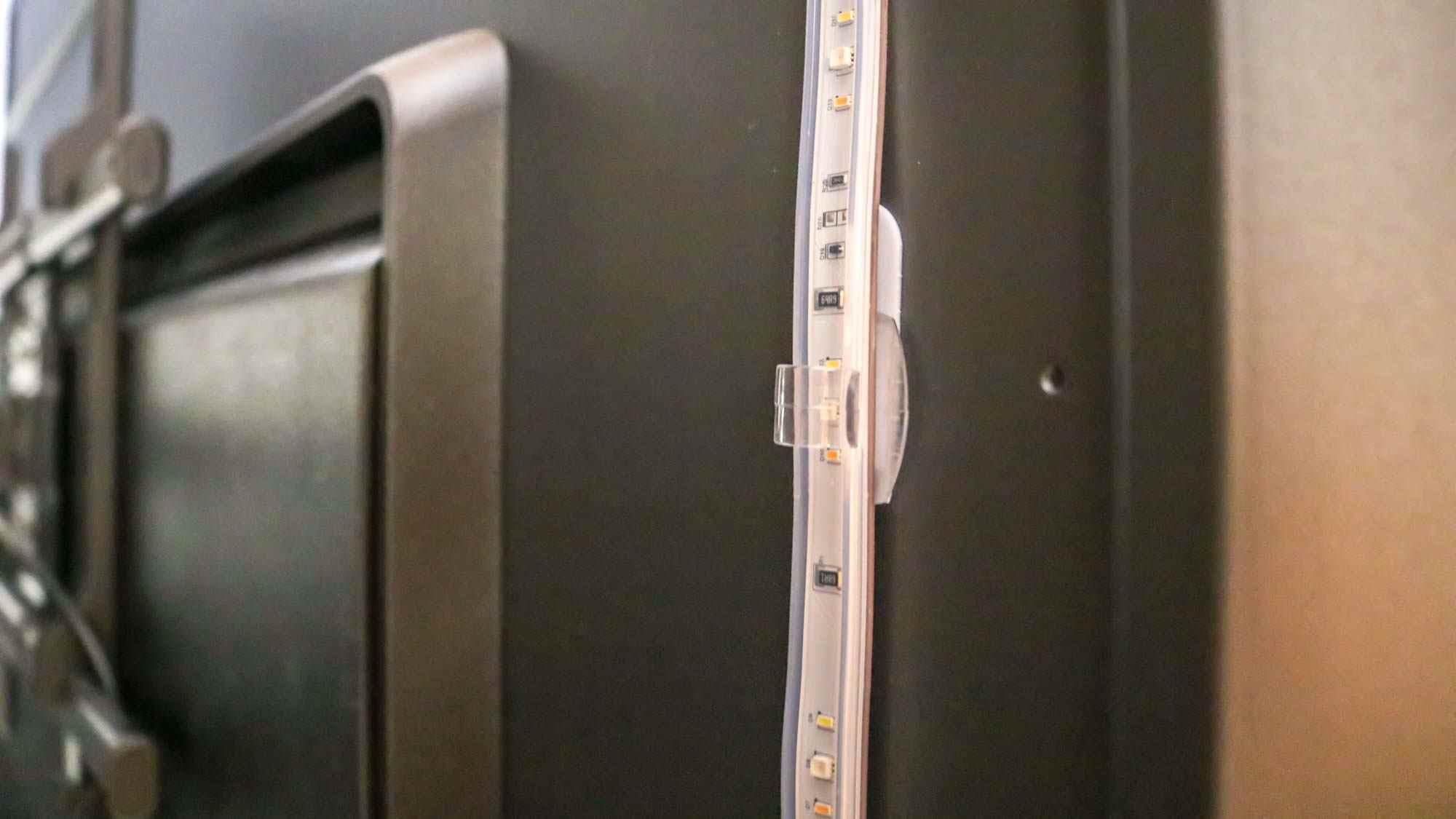 Un clip transparent attaché à un téléviseur tenant une bande lumineuse