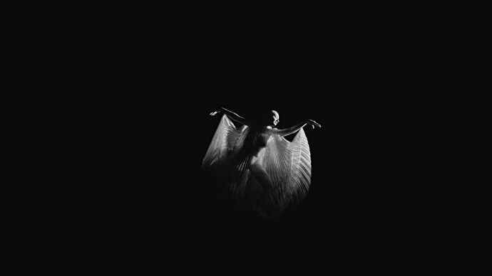 Une femme danse dans une cape flottante transparente, dans un vide noir, extrait d'un clip d'Immortality