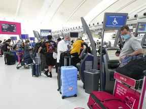 Aux États-Unis, les législateurs et les défenseurs augmentent la pression sur le gouvernement fédéral pour réduire les retards de voyage entre les États-Unis et le Canada.  Les gens font la queue pour s'enregistrer à l'aéroport international Pearson de Toronto le jeudi 12 mai 2022.