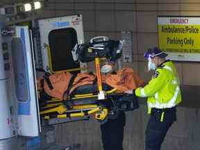 Les ambulanciers paramédicaux transfèrent un patient de leur ambulance au service des urgences de l'hôpital Michael Garron pendant la pandémie de COVID-19 à Toronto.