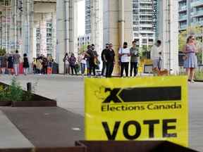 Des gens font la queue devant un bureau de vote pour voter lors d'une élection fédérale, à Toronto, le 20 septembre 2021.