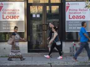 Des gens passent devant des panneaux bilingues pour un espace commercial à louer dans la ville de Westmount sur l'île de Montréal le 5 août 2022.
