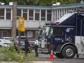 Des enquêteurs de la police sur les lieux où un homme de 26 ans a été tué après avoir été abattu par la police de Montréal dans le stationnement d'un motel de l'arrondissement St-Laurent tôt le jeudi 4 août 2022.