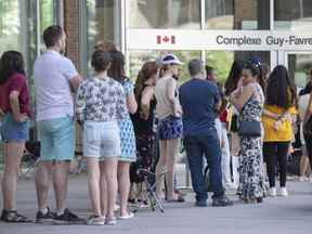 Le gouvernement fédéral ajoute de nouveaux points de service de passeport à travers le Canada alors que la forte réaction contre les longs délais d'attente se poursuit.  Des gens font la queue devant l'édifice fédéral Guy Favreau en attendant de faire une demande de passeport à Montréal, le dimanche 26 juin 2022.