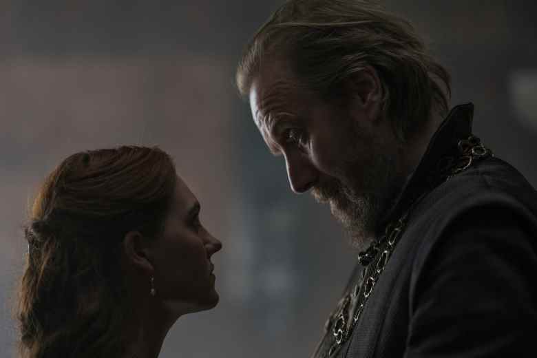 Un homme parle étroitement avec sa fille adolescente, toutes deux en tenue médiévale à l'intérieur d'un palais ;  encore de 