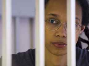 La basketteuse américaine Brittney Griner regarde à travers les barreaux alors qu'elle écoute le verdict debout dans une cage dans une salle d'audience à Khimki, près de Moscou, en Russie, le jeudi 4 août 2022.