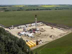 Une plate-forme de forage pétrolier fonctionne entourée de champs de canola et de foin près de Cremona, en Alberta.