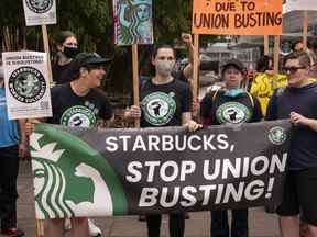 Des manifestants protestent devant un Starbucks fermé à Seattle, Washington en juillet.  Le groupe soutenant la campagne syndicale allègue que Starbucks a fermé des magasins pour contrecarrer les efforts de syndicalisation.  L'entreprise nie les allégations.