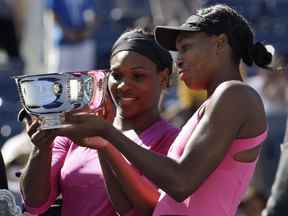 Serena Williams, à gauche, et sa sœur Venus examinent le trophée du championnat après avoir remporté l'US Open à New York, le lundi 14 septembre 2009.