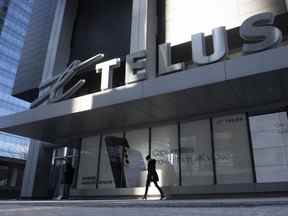 Une femme passe devant le siège social de Telus à Toronto le 11 février 2021. Telus Corp. veut répercuter les frais de carte de crédit sur les clients et prévoit d'y ajouter 1,5 % 