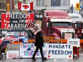 Un manifestant marche devant des camions garés alors que des manifestants protestent contre les restrictions liées au COVID-19, à Ottawa le 8 février 2022.