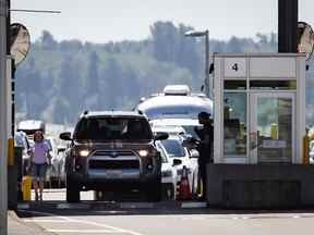 Un agent de l'Agence des services frontaliers du Canada parle à un automobiliste entrant au Canada au poste frontalier Douglas-Peace Arch à Surrey, en Colombie-Britannique, le 9 août 2021.