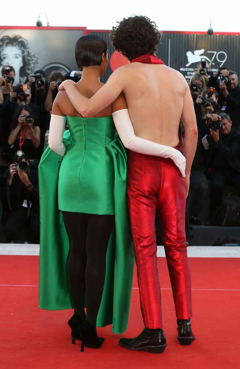 Dos de Taylor Russell, à gauche, dans une robe verte Balenciaga et de Timothee Chalamet, à droite, dans un ensemble Haider Ackermann rouge dos nu.