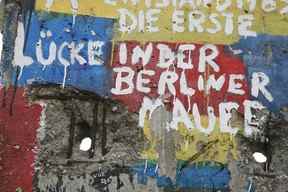 Graffitis et salutations sur l'une des sections restantes du mur de Berlin.  Le texte allemand dit : « Les premiers trous dans le mur de Berlin ».  GETTY IMAGES