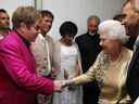 La reine Elizabeth II rencontre Sir Elton John dans les coulisses en tant que chanteur britannique Robbie Williams, à droite, regarde pendant le concert du jubilé de diamant devant le palais de Buckingham à Londres, le 4 juin 2012. 
