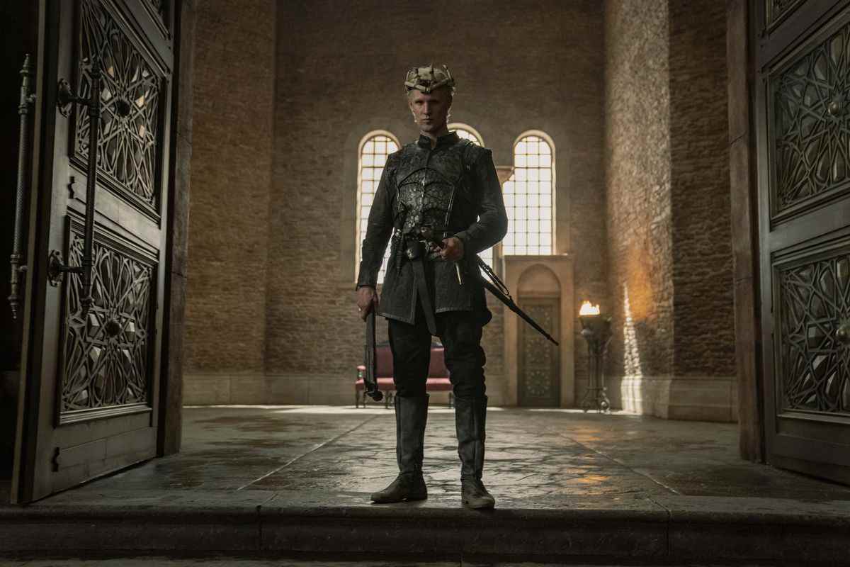 Démon debout dans l'embrasure de la grande salle avec sa main sur son épée et portant une hache et portant une couronne en os