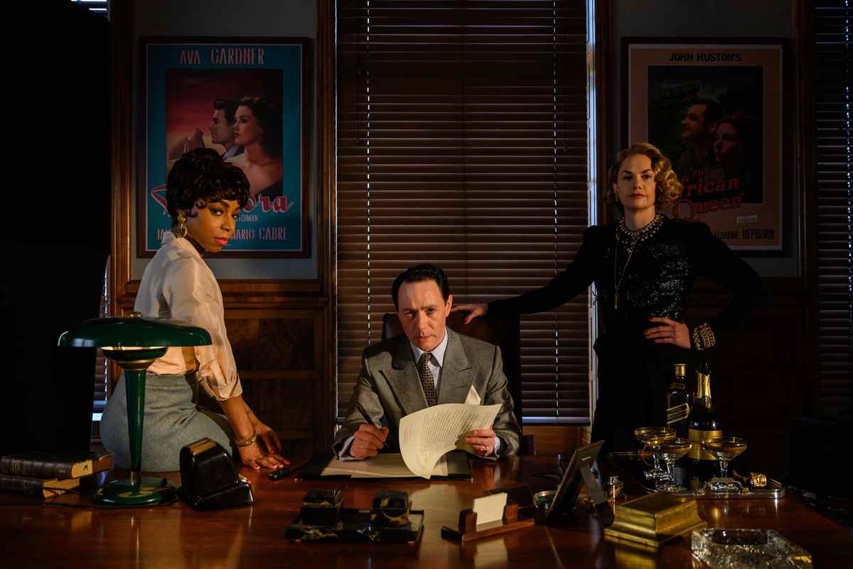 John Woolf (Reece Shearsmith), Petula Spencer (Rita Wilson) et Ann Saville (Pippa Bennett-Warner) regardent derrière le grand bureau brillant de Woolf