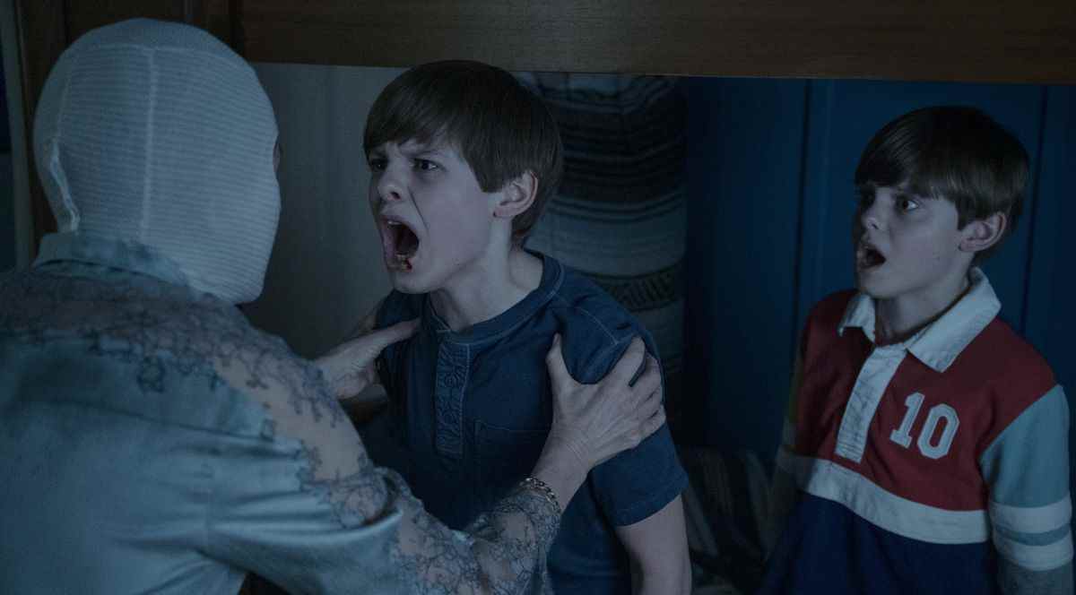 La mère (Naomi Watts) tient l'un de ses jumeaux alors qu'il lui crie au visage, tandis que l'autre regarde sous le choc, dans Goodnight Mommy 2022