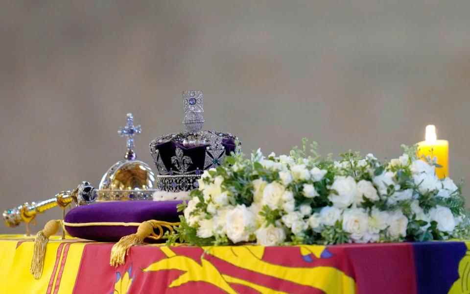 Le cercueil de la reine Elizabeth II, drapé de l'étendard royal avec la couronne impériale d'État et l'orbe et le sceptre du souverain, est exposé sur le catafalque alors que les membres du public défilent dans le Westminster Hall, au palais de Westminster - AFP