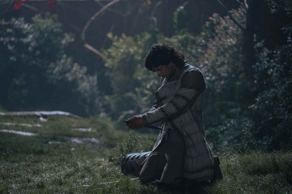 Ser Criston Cole tient un couteau sur son estomac dans une zone herbeuse de House of the Dragon.