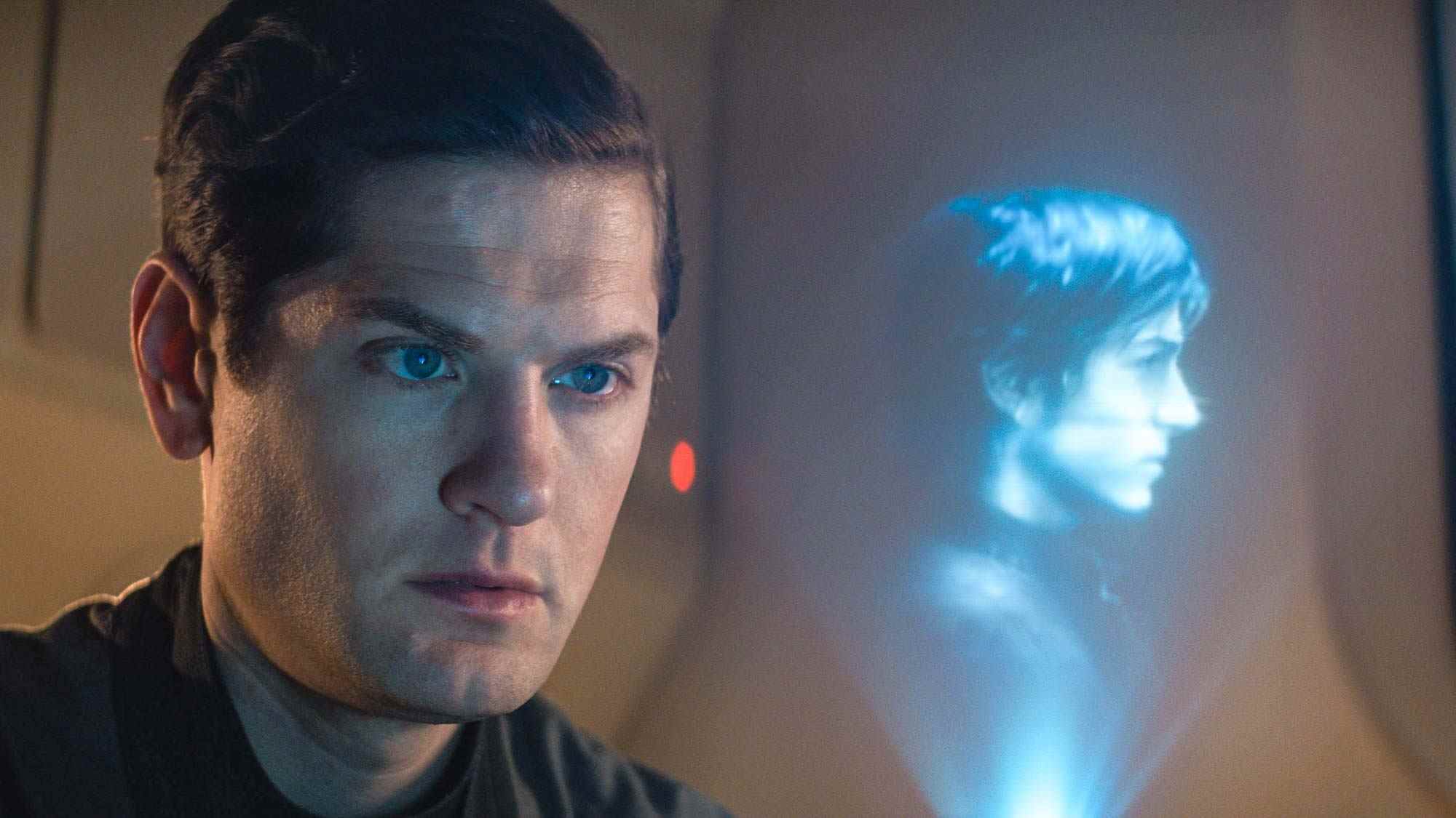Kyle Soller dans le rôle de Syril Karn regardant un hologramme de Diego Luna dans le rôle de Cassian Andor à Andor