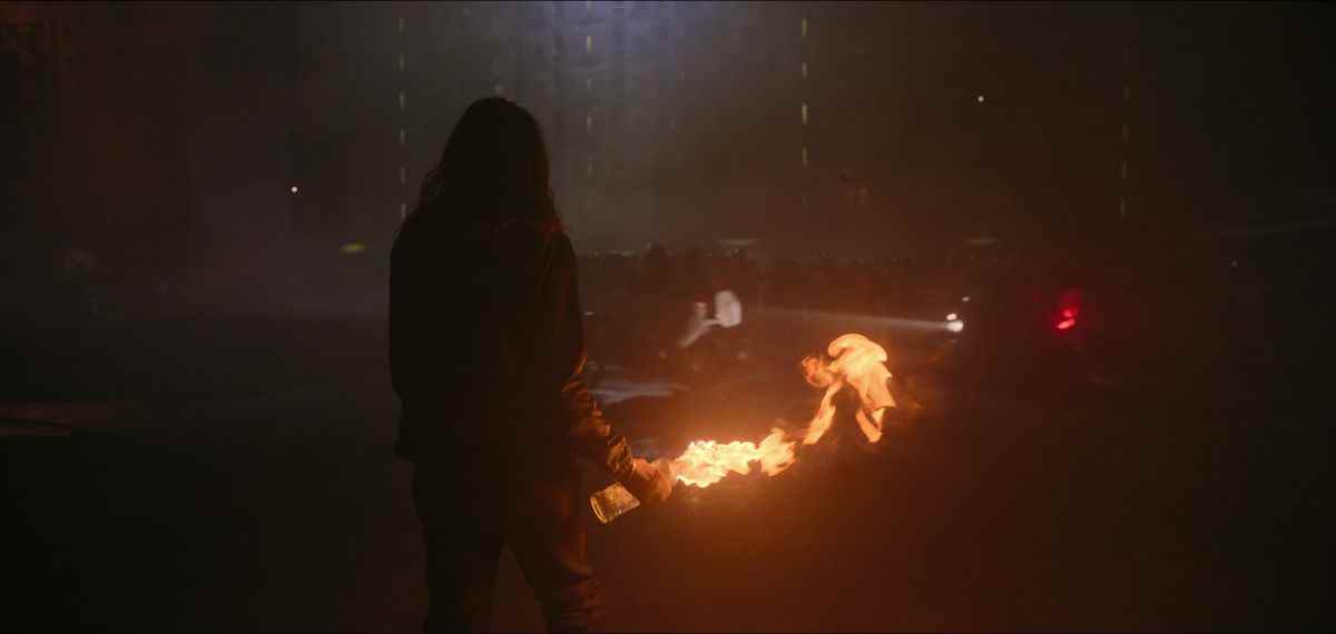 Une silhouette tenant un cocktail Molotov enflammé se dresse dans les rues de Paris à Athena