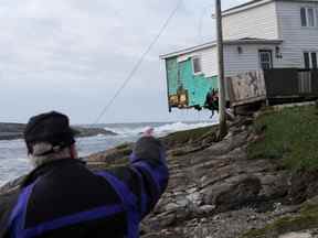 Une personne pointe vers une maison endommagée après l'arrivée de l'ouragan Fiona à Port Aux Basques, Terre-Neuve, Canada le 25 septembre 2022.