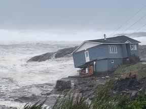 Des vagues roulent près d'une maison endommagée construite près du rivage alors que l'ouragan Fiona, plus tard déclassé en cyclone post-tropical, passe la colonie atlantique de Port aux Basques, Terre-Neuve-et-Labrador, Canada le 24 septembre 2022.