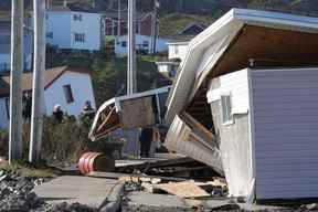 Les gens retirent des objets des bâtiments endommagés qui ont été déplacés de leur position à la suite de l'ouragan Fiona à Port Aux Basques, Terre-Neuve-et-Labrador, le dimanche 25 septembre 2022.