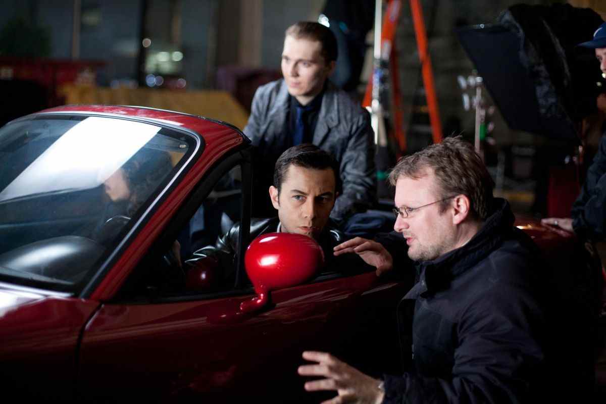 Une photo des coulisses du réalisateur Rian Johnson dirigeant Joseph Gordon-Levitt et Paul Dano dans une Mazda MX5 rouge.