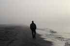 Homme seul marchant sur une plage brumeuse